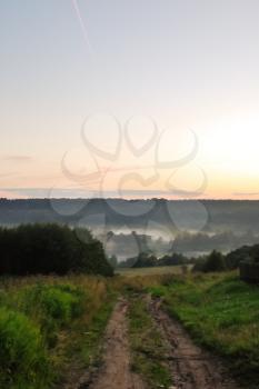 country road and fog over river in summer twilight, Russia