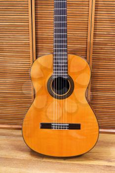 classical acoustic guitar near wooden wall