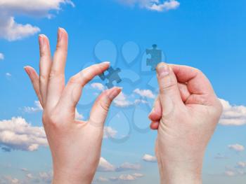 male and female hands with little puzzle pieces with blue sky background