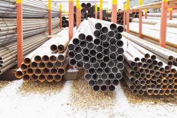 piles of metal pipes in outdoor warehouse in winter