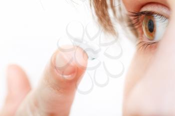 girl inserts contact lens in eye close up