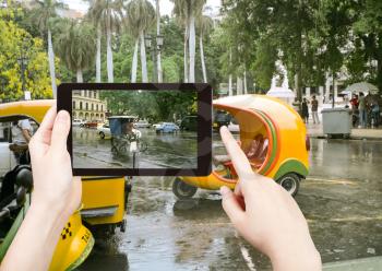 travel concept - tourist taking photo of Havana street in rain on mobile gadget, Cuba