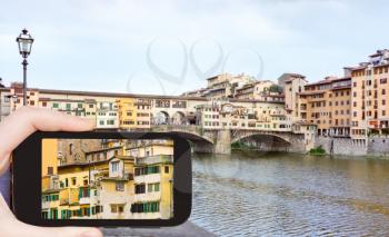 travel concept - tourist taking photo of bridgew Ponte Vecchio in Florence on mobile gadget