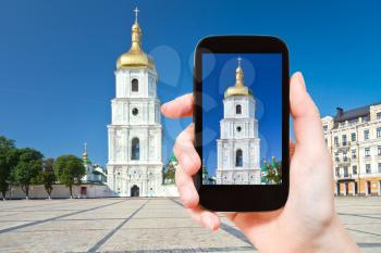 travel concept - tourist taking photo of Bell Tower of Saint Sophia Cathedral in Kiev on mobile gadget, Ukraine