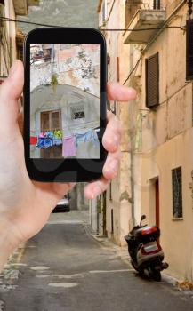 travel concept - tourist taking photo of small side street in italian town San Felice Circeo on mobile gadget, Italy