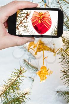 travel concept - tourist taking photo of Christmas tree decoration outdoors on mobile gadget