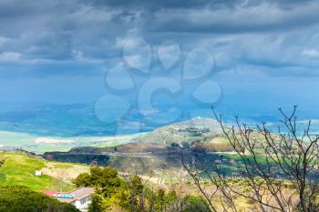 dark blue rainy clouds over green sicilian hills in spring, Aidone, Italy