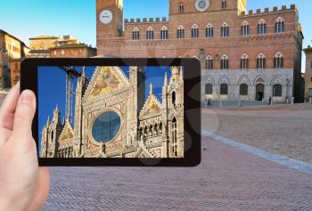 travel concept - tourist takes picture of Cathedral of Siena and Piazza del Campo - Europe's greatest medieval squares, Siena, Italy, on tablet pc