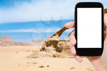 travel concept - tourist photograph Bridge rock in Wadi Rum desert, Jordan on smartphone with cut out screen with blank place for advertising logo