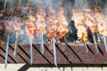 many shish kebab sticks preparing on outdoor grill