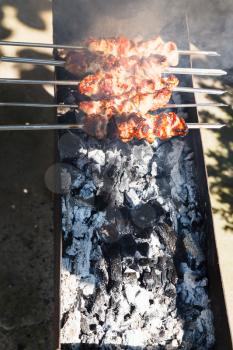 several kebab sticks preparing on outdoor grill