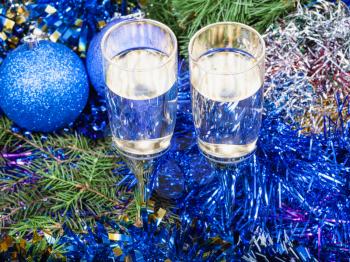 Christmas still life - above view of two glasses of champagne with blue Xmas decorations on Christmas tree background