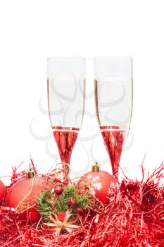 two glasses of champagne and angel figure at red Christmas balls and tinsel isolated on white background