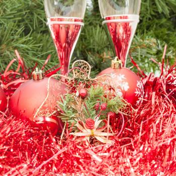 Christmas still life - Two glasses of sparkling wine with red Xmas decorations on Christmas tree background