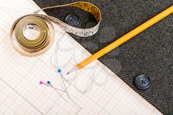 dressmaking still life - top view of cutting table with pattern, measure tape, pencil, pins, tweed jacket