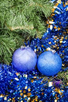 Christmas still life - two blue and violet Christmas baubles, tinsel on Xmas tree background