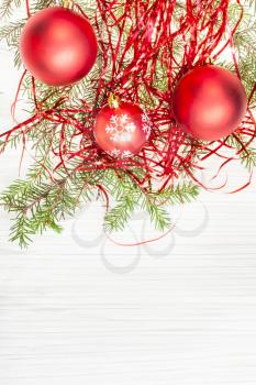 Christmas greeting card - border from three red Xmas balls and tree branch on blank paper background