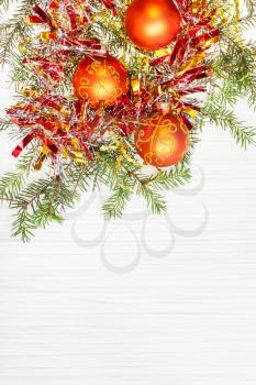 Christmas greeting card - border from three orange Xmas baubles and tree branch on blank paper background
