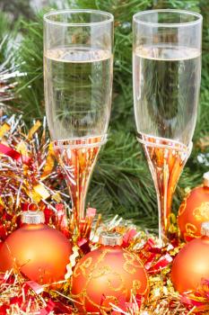 Christmas still life - golden Xmas baubles and tinsel and two glasses of sparkling wine on Christmas tree background