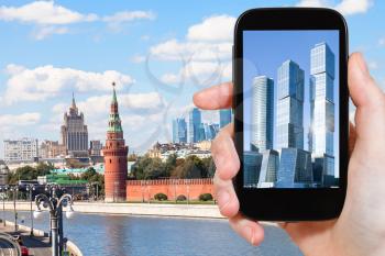 travel concept - tourist photographs picture of Moscow City on smartphone