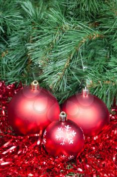 vertical Christmas still life - three red Christmas balls, tinsel on Xmas tree background