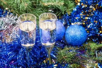 Christmas still life - above view of two glasses of champagne with blue Xmas balls and tinsel on Christmas tree background