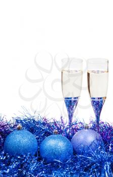 two glasses of sparkling wine at blue and violet Christmas balls and tinsel isolated on white background