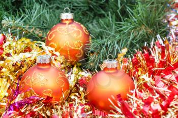 Christmas still life - few orange and yellow Christmas balls, red tinsel on green Xmas tree background