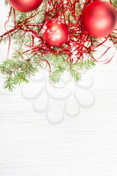 Christmas greeting card - border from red Xmas decorations and tree branch on blank paper background