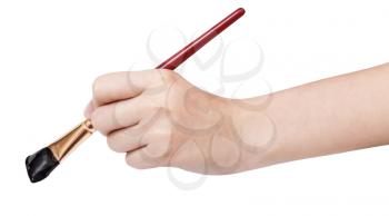 hand holds artistic flat paintbrush with black painted tip isolated on white background