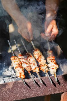 chef cooks pork shish kebabs on outdoor brazier