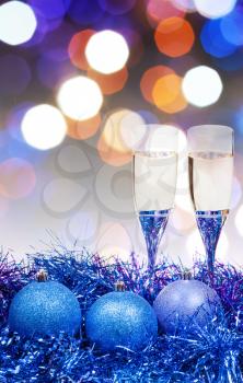 Christmas still life - two glasses of sparkling wine at blue Xmas decorations with pink and violet blurred Christmas lights bokeh background