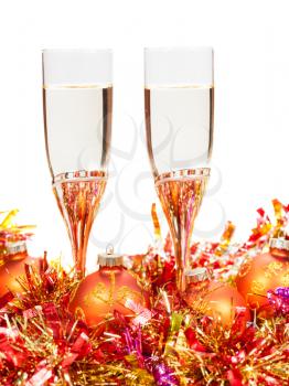 two glasses of sparkling wine at pink and orange Christmas balls and tinsel isolated on white background