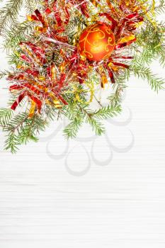 Christmas greeting card - border from one orange Xmas ball and tree branch on blank paper background