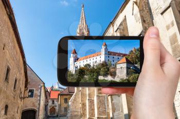 travel concept - tourist snapshot of Bratislava Hrad castle from Farska street in old town on smartphone