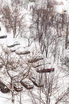 above view of cars covered with snow in parking lots in city