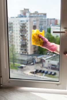 washing home window in spring - washer cleans window frame by rag in apartment house