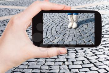 travel concept - tourist photographs cobble stone pavement of Palace Square in Saint Petersburg, Russia on smartphone