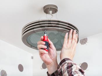 Electrician mounts round ceiling light in room