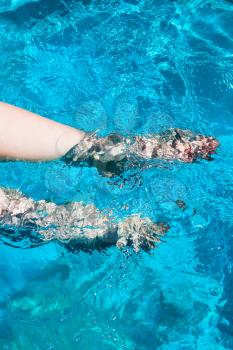 outdoor swimming pool - female legs flounder in blue water in sunny summer day