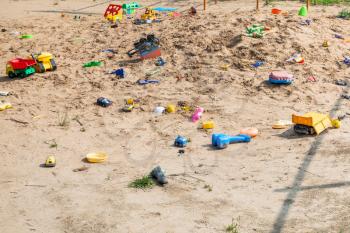 abandoned toys in outdoor sand playground in summer day