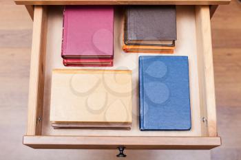 above view of pack ofl little books in open drawer of nightstand