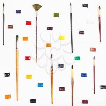 many paint brushes and watercolors arranged on white background