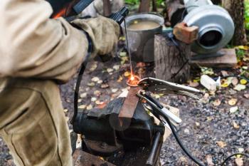 Welder welds iron ring by spot electric welding in outdoor rural workshop