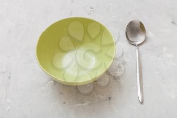 green bowl and steel spoon on gray concrete plate