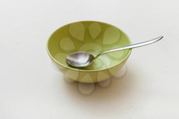 green bowl with spoon on white plastering plate