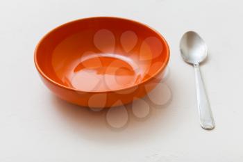 orange bowl and spoon on white plastering plate