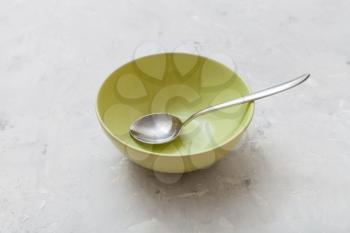 green bowl with metal spoon on gray concrete plate