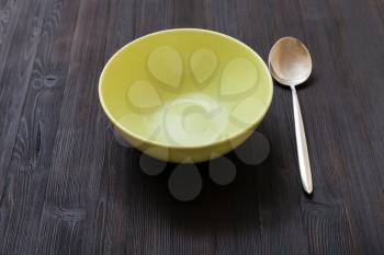 one green bowl and spoon on dark brown board
