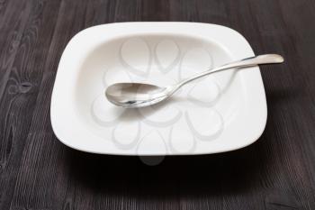 one white bowl with spoon on dark brown board